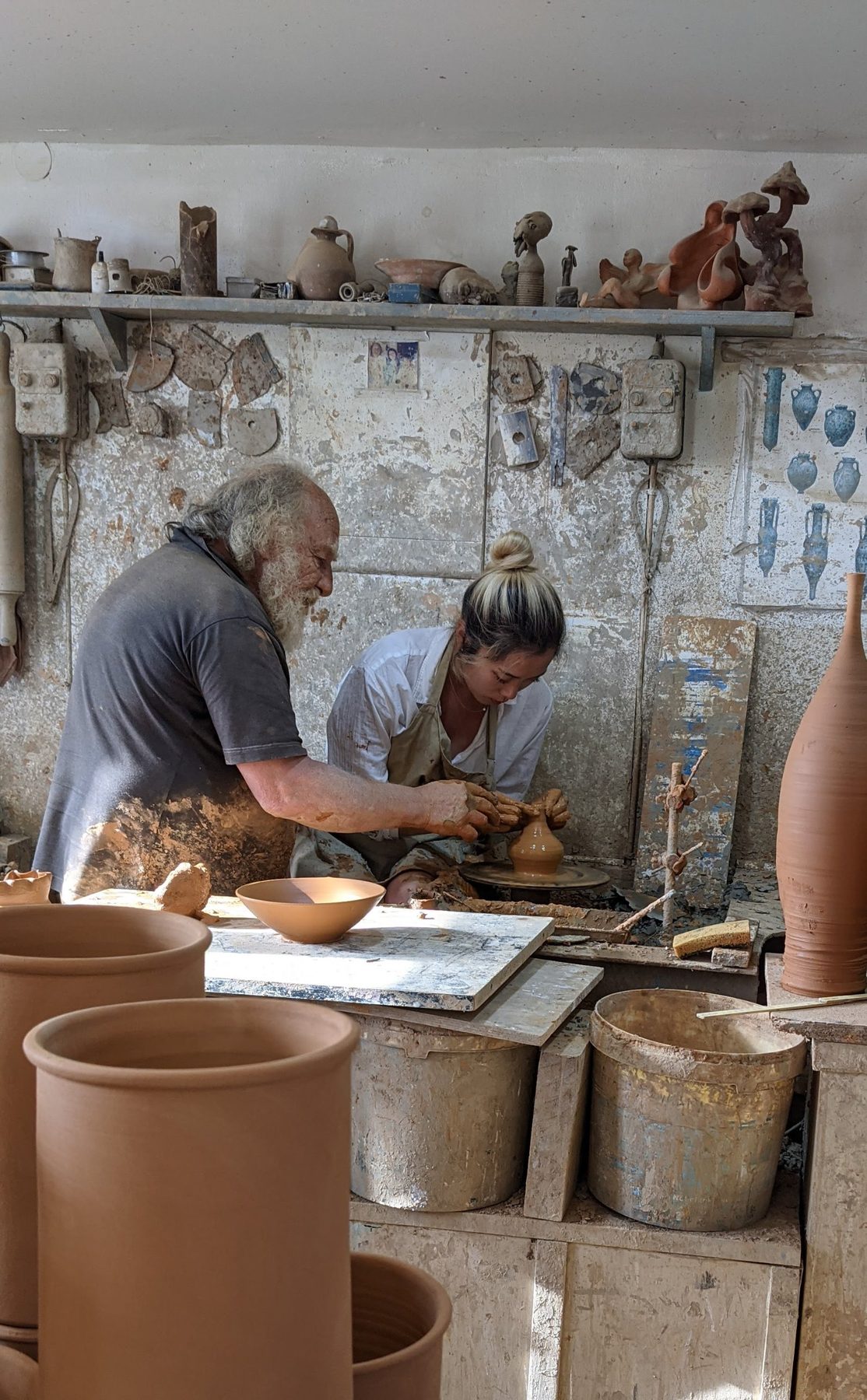 Ruth Kim shaping a piece on the wheel, guided by her teacher