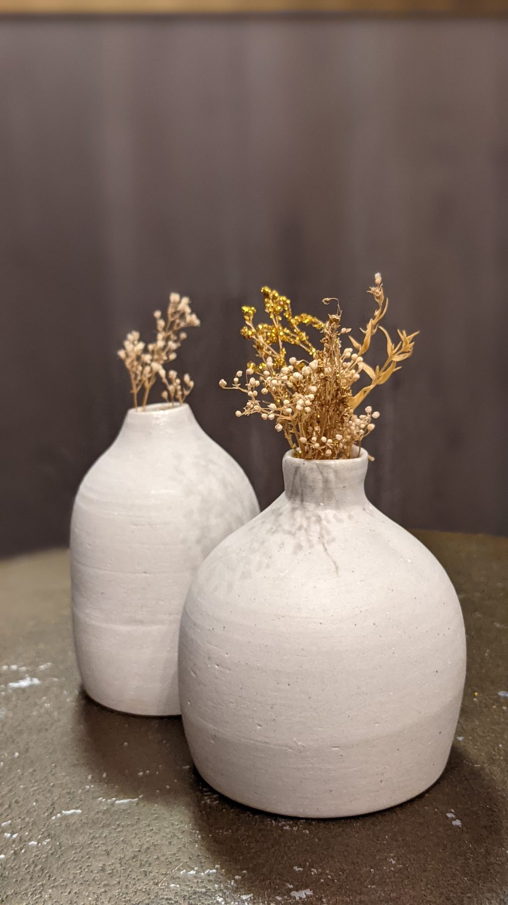 Pair of small unglazed stoneware bud vases with dried flowers