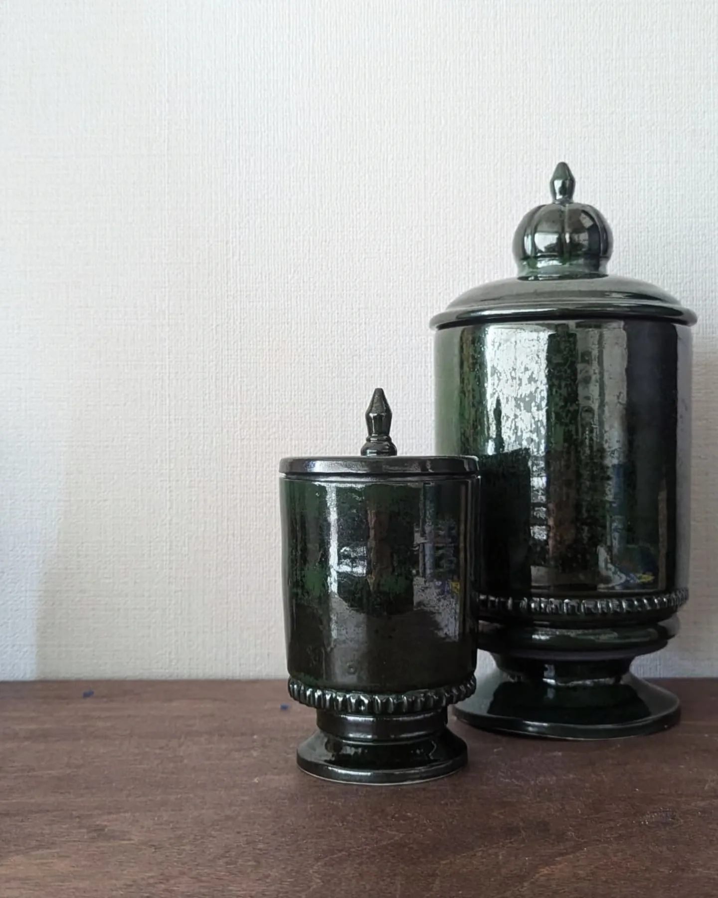 Two covered jars in a deep forest green glaze, one tall and one short